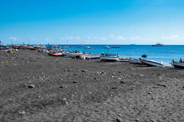 Obraz premium View of the black sand beach of the Vulcano Island, small volcanic island, located in the Mediterranean Sea, between Sicily and Calabria Regions (Southern Italy), with it turquoise clear waters.