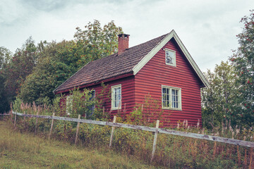 old red small house in the woods by a field