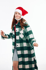 smiling woman santa hat plaid coat posing light background