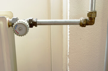 Grey knob of a heating radiator with pipe at home