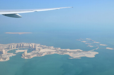 Naklejka premium The Pearl-Qatar island in Doha through the airplane porthole, aerial view