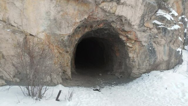 An abandoned mine in the mountains. The drone flies away from the entrance to the mine. The entrance to the cave is located in the Kungei Alatau Mountains in Kazakhstan, located within the reach of La