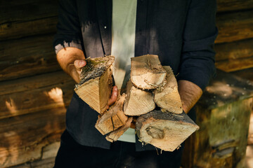 A man holds in hand firewood for a future bonfire. Preparing to light a fire in the fireplace. The...