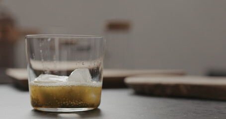 ice into lulo fruit pulp in tumbler glass on concrete countertop