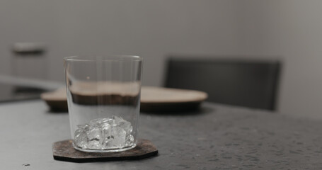 ice into tumbler glass on concrete countertop