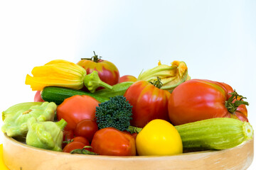 Wooden plate with fresh vegetables - tomatoes, zucchini, broccoli, and squash