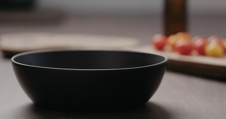 making salad with kale, and cherry tomatoes in black bowl on concrete countertop