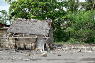 Wrecked bamboo hut, driftwoods and ocean debris along sea shore