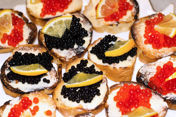 Caviar sandwiches garnished with lemon. Treats on the festive table. A delicacy treat for Christmas and New Years. Flat layout. Top view. Close-up.