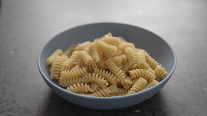 boiled fusilli pasta in blue bowl on concrete background