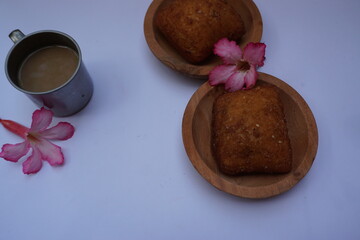 Frangipani flowers, cup of coffee and "Bolangbaling" bread in a wooden plate isolated on a white background.