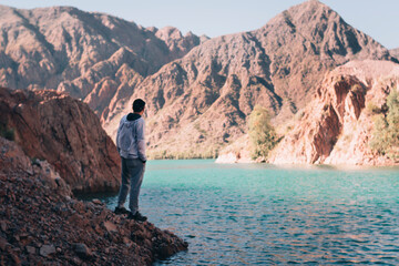 man standing in front of lake between mountains