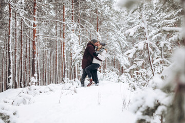 Loving young couple walks in a beautiful snowy forest in winter