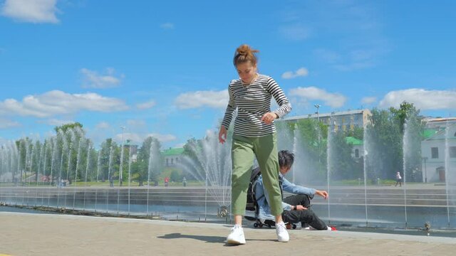 The girl dances hip-hop and enjoys life in the park on the city promenade. The concept of emotions, impressions, carefree and city life