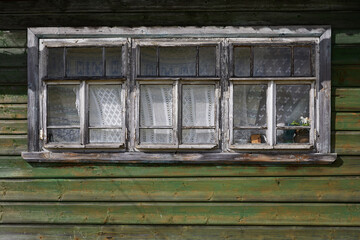 Windows in a traditional wooden house in a Russian village. Old wooden Windows with peeling paint and white curtains