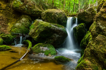 nice waterfall with huge rocks with green moss in a forest