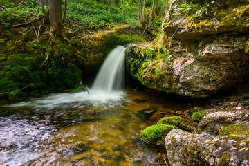 Fototapeta premium little waterfall with shallow water and rocks with green moss
