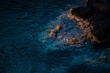 Sunset seascape with sea water in motion blur, stones on the beach. Atlantic ocean, Tenerife island. Long exposure. Background
