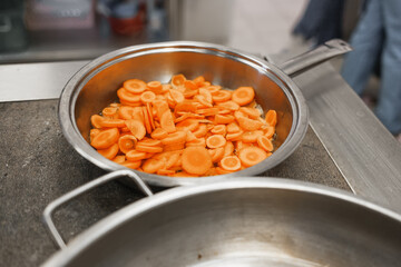 Cooking in the dining room. Sliced pieces of carrots are in the pan. Close-up of vegetables
