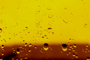 Yellow background with water drops on the glass. The heel is design for beer. Close-up