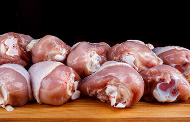 Raw chicken legs are laid in 2 layers on a wooden cutting board.