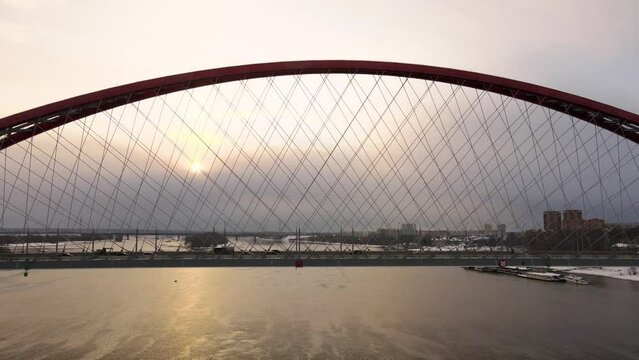 Aerial photography in 4k. Silhouette of the bridge on a background of gray sky and sun