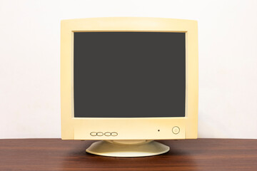 Old computer monitor empty on wooden table in front of white wall in the house. CRT monitor with cut out screen