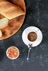 Breakfast. Fresh homemade bread and cup of coffee on a black background. Butter and sweet. Flat lay. Top view. Vertical orientation