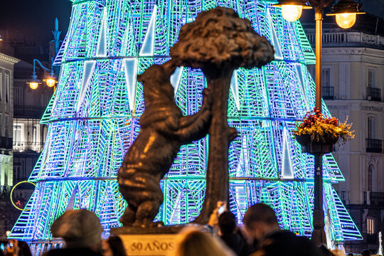Estatua del oso y el madroño de la Puerta de Sol de Madrid, con el árbol azul y verde detrás durante las navidades