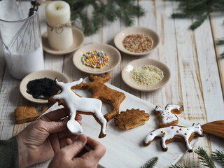 An elderly woman prepares for the holiday of Christmas or New year and is engaged in decorating homemade cookies in the form of animals.