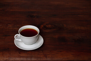 A white Cup of tea on a brown wooden table. Copy space.