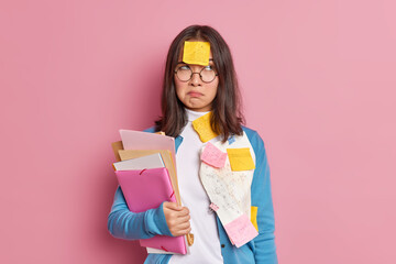 Frustrated female manager has remote work poses with paper documents checks information and...
