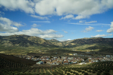 Landscape with mountains, village in a valley and blue sky with clouds