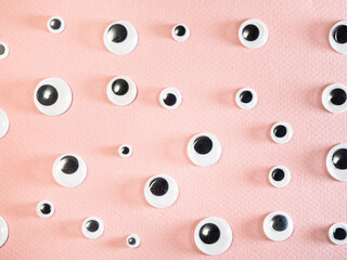 many flat plastic doll eyes on pink paper background