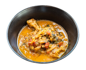 cooked Chakhokhbili (traditional georgian dish from stewed chicken meat, tomato, eggplant and fresh herbs) in black bowl cutout on white background
