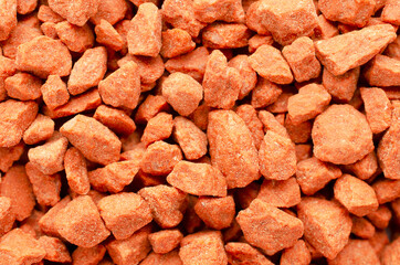 Potassium chloride is a red mineral fertilizer close-up. Red background of fertilizer potassium chloride. Texture of granular potassium chloride is red. Macro texture. Background mineral fertilizers.
