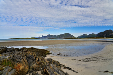 large deserted beach on the Versteralen with mountains in the background and a cloudy blue sky