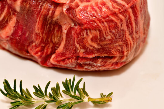 Close up image of a filet mignon, uncooked on a white dish.