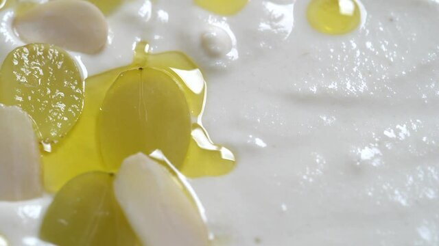 Traditional Spanish dish, cold soup ajo blanco or ajoblanco from garlic, almonds, white wine vinegar, olive oil and green grapes in a bowl with a spoon, close up, rotate