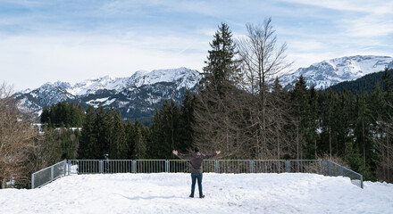 Happy young man enjoying the winter with the alps in the background, Allgäu, Germany