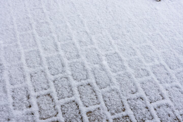 Close up view of beautiful snow covered paving slabs. Winter pattern texture concept.