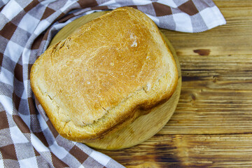 Homemade loaf of bread on a wooden table freshly baked in an electric bread maker. Homemade baking