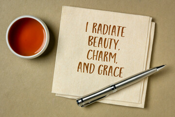 I radiate beauty, charm and grace - positive affirmation, handwriting on a napkin with a cup of tea, positivity and personal development concept