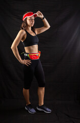 Beautiful redhead girl in jogging uniform posing in studio on black background
