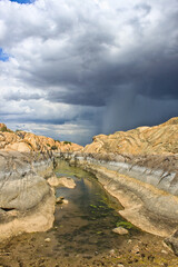 Stream in rock formations with incoming rain storm. - 401803794