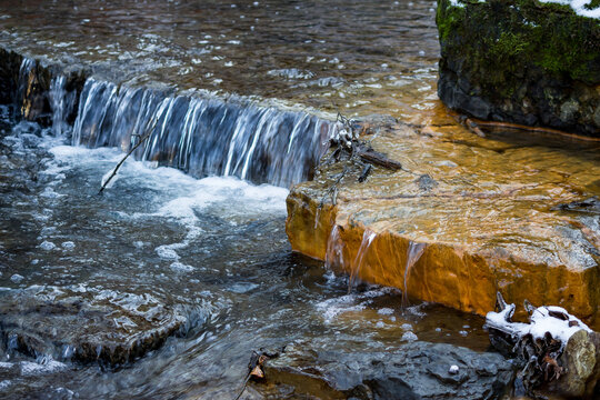 Small waterfalls on the river, limestone layers painted in orange with iron ochre
