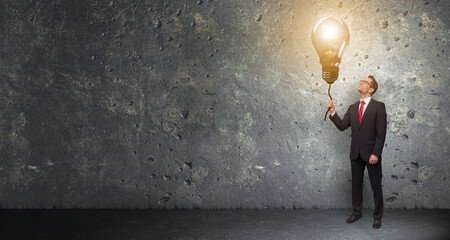 Gründer hält leuchtende Glühbirne an einer Schnur in der Hand