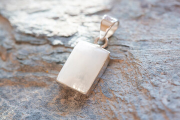 Sterling silver pendant with mineral moon stone gemstone on rocky background