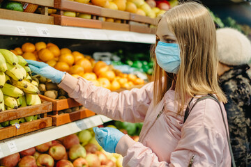Young girl in medical masks makes purchases in a supermarket in search of food.