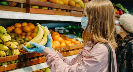 Young girl in medical masks makes purchases in a supermarket in search of food.